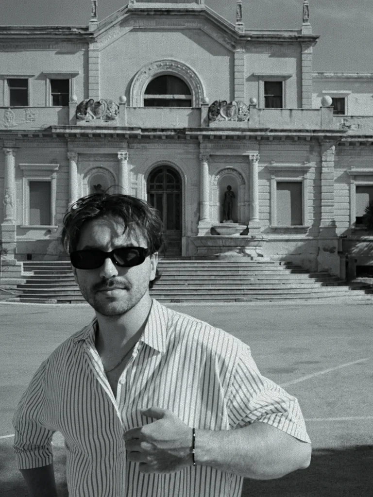 Filip in a striped shirt and sunglasses in front of an old palace