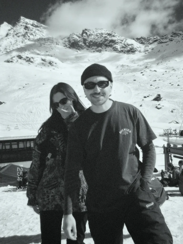 Filip in a beanie and sunglasses on a snowy mountain slope, black and white